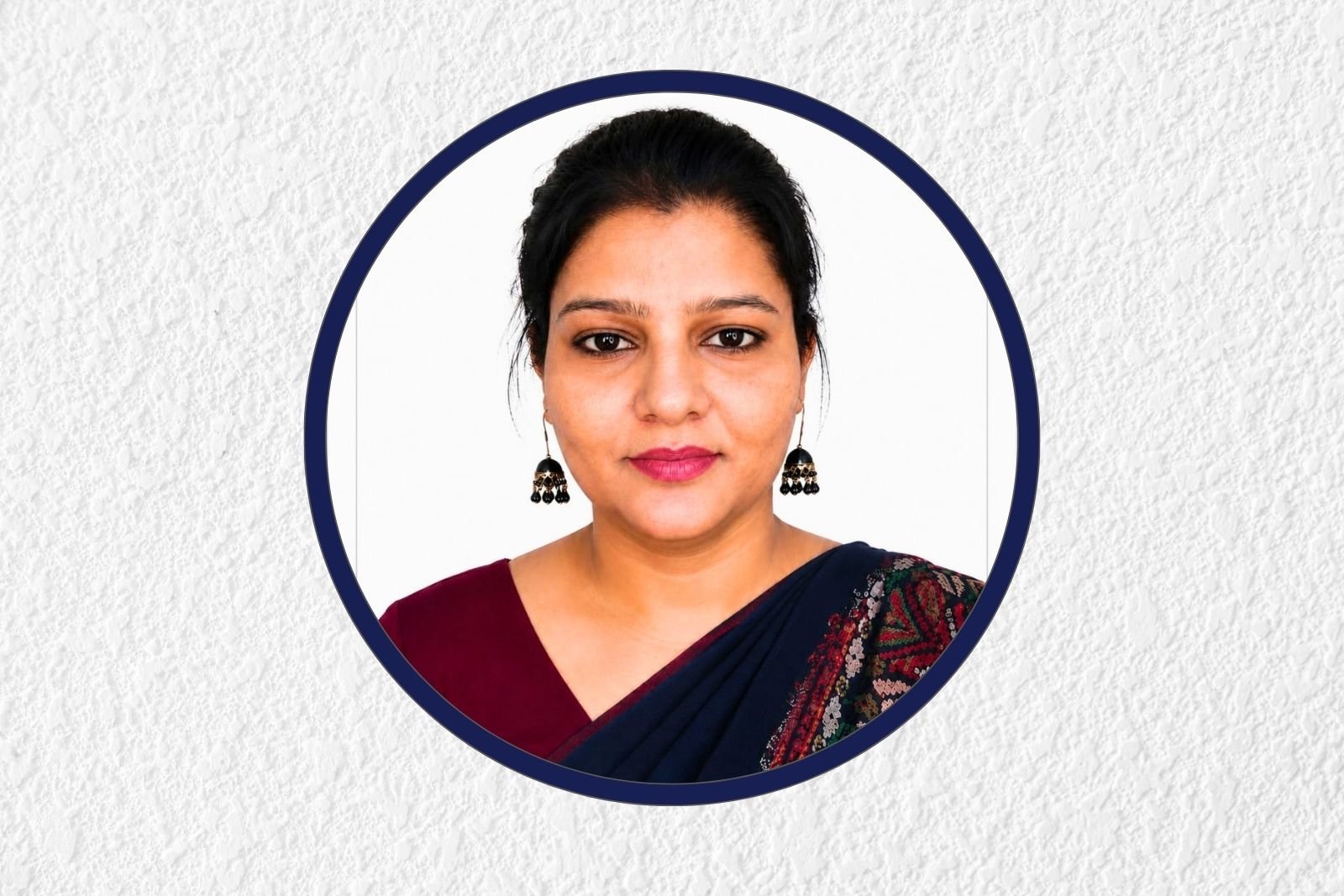 Portrait of a woman with dark hair wearing a navy saree and black earrings, framed by a blue circular border.
