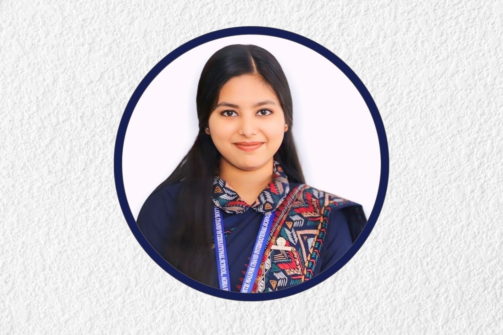 Smiling young woman with long dark hair, wearing a colorful patterned scarf and lanyard, framed by a circular navy border on a white background.